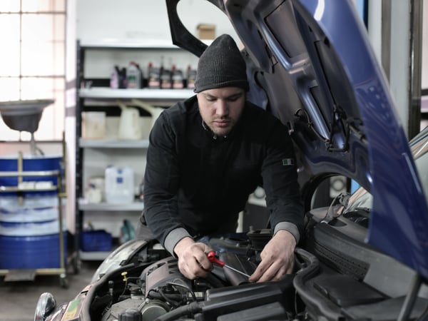 Man working under car hood in a garage, focused