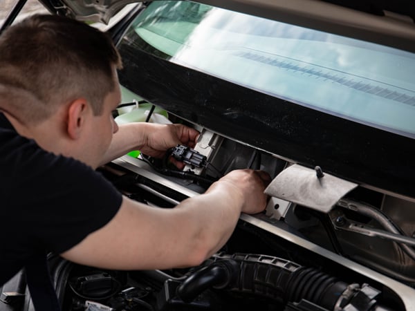 A mechanic working on car engine repairs inside