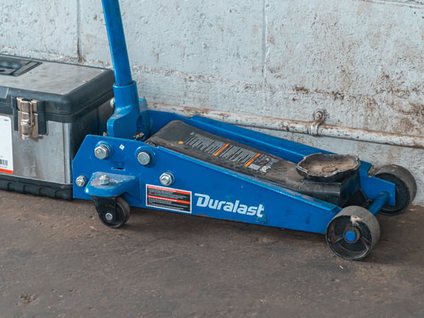 A blue hydraulic floor jack with a toolbox